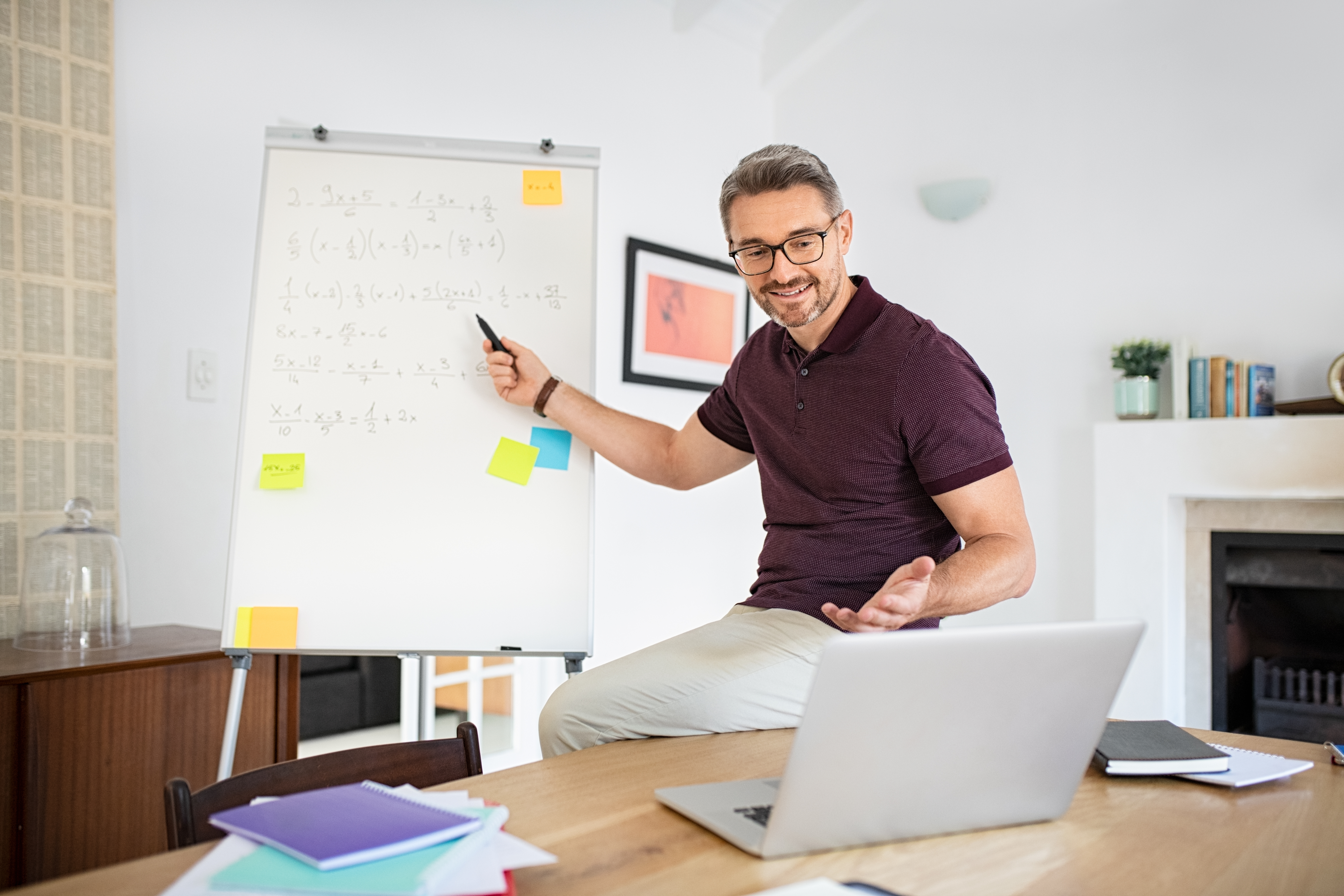 Mature teacher having online class through video call and explaining maths. Teacher teaching students maths on video call at home: e-learning via interactive platform. Mature math professor teaching.